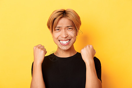 幸运快乐的亚洲人赢得奖项 做拳手泵式的姿势和笑笑的满足感 胜过成就 站立在黄色背景上发型成人职业工作室优胜者情感学生金发教育员工图片