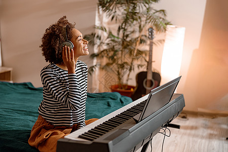 在家耳机里玩合成器的开心女人艺术家卧室天赋微笑乐器钢琴家词曲作曲家玩家演员图片