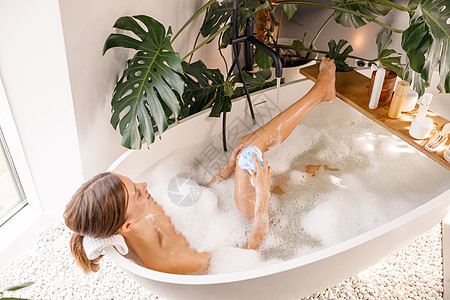 使用海绵的感性年轻女子 在豪华温泉度假村享受用肥皂泡沫洗澡图片