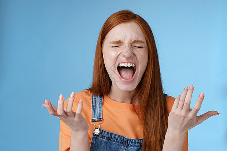 生气愤怒的喜怒无常的红发女孩大喊抱怨愤怒站着烦恼大声尖叫闭上眼睛大声喊叫向侧面举起双手沮丧完全难以置信感到被欺骗痛苦的背叛头发快图片