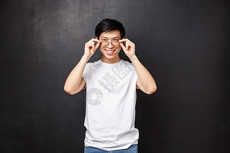 帅气的亚洲年轻帅哥在眼镜店挑选新的处方眼镜 戴上眼镜 看起来自信而高兴的镜头 微笑的白牙 黑色背景图片