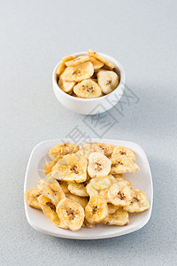海南香蕉白碗中烤香蕉薯片和桌上的碟子 快餐 网络横幅 垂直视图背景