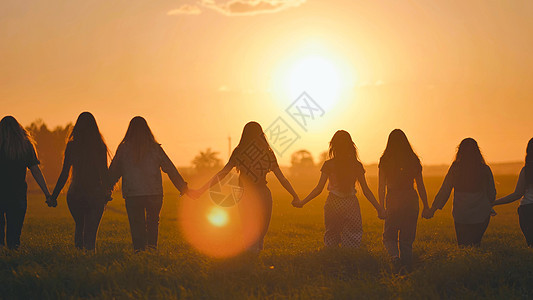 一群女孩在日落时手牵手朝太阳走去男人家庭天空游客背包女性幸福孩子们自由远足生活方式高清图片素材