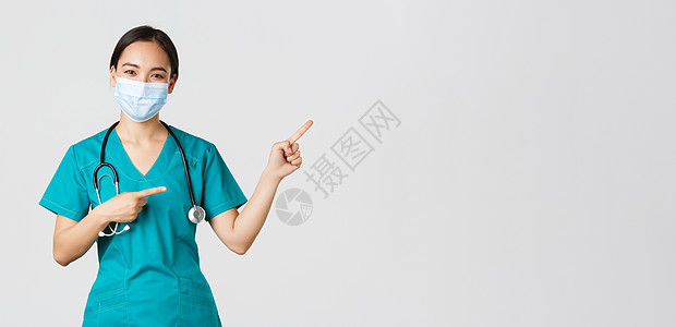 Covid19 冠状病毒病 医护人员的概念 令人愉快的亚洲女医生 穿着磨砂膏和面具的医务人员 指着右上角 展示广告学生疾病暴发隔图片