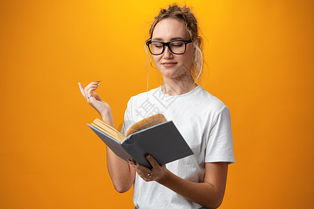 有黄色背景书籍的可爱漂亮美美女孩隐藏青少年孩子快乐学生大学教育微笑笔记本瞳孔图片