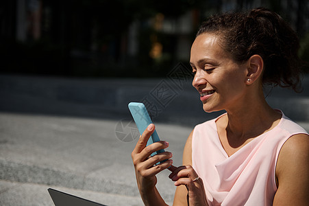 在智能手机上打扫的美美美非洲女性 迷人而愉快的混合种族女性在户外使用移动电话图片