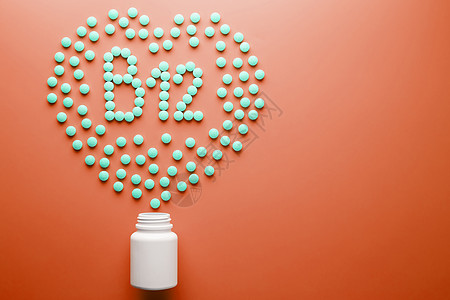红色药片B12维生素 以心脏的形状 在红色基质上 从白色罐子里倒出来食物营养药片颗粒制药药店标签托盘药物治疗背景