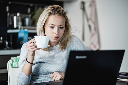 女自由职业者穿着临时家庭服 上午从餐桌上搬起工作 背景是家用厨房在餐厅里互联网隔离企业家人士杯子笔记本女性阅读商业职业者图片