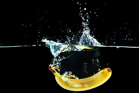 香蕉掉入水中 在黑色背景下喷洒着飞溅图片