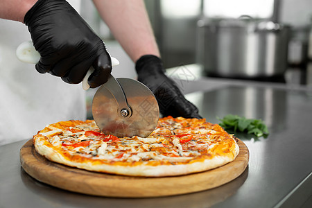 厨房的厨师切开的紧贴手 是新准备的披萨切片图片