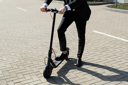 穿着商业西装和鞋贴近一个男人的脚 在一辆电动摩托车旁边潮人工具男性运动城市电话活力运输车轮活动图片