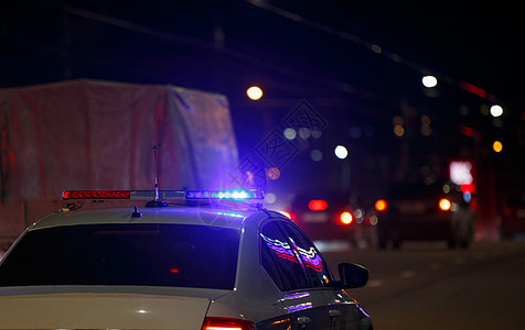 无法修复的公路警车 夜间城市道路屋顶上开着红灯和蓝色警报灯图片