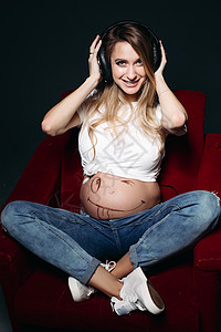 肚子上有大耳机的孕妇微笑着幸福闲暇情感希望孩子女士母亲压痛身体婴儿图片