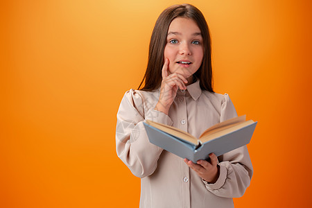 有着橙色背景书籍的聪明少女女孩的肖像孩子们童年考试孩子教育文学瞳孔学生头发家庭作业图片