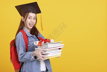 毕业帽子的亚洲快乐女大学生微笑和持有书本 笑着笑着笑着拿着书图片