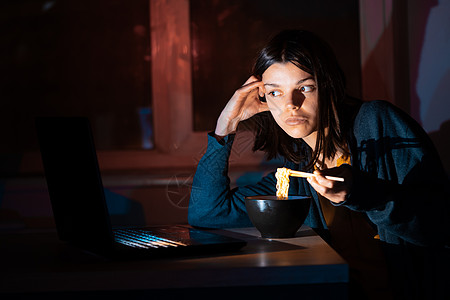女孩在笔记本电脑上吃面和看录像职场技术失眠办公室电视节目送货互联网视频人士桌子图片
