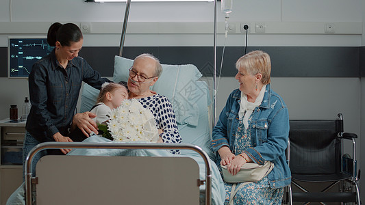 家庭探访老年病人 在医院病房床上送花和鲜花图片
