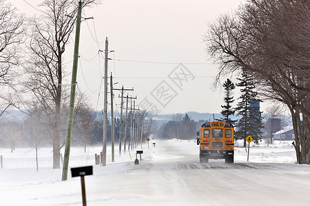 校车在一条乡村公路上行驶 有雪地漂浮和冬季吹雪图片