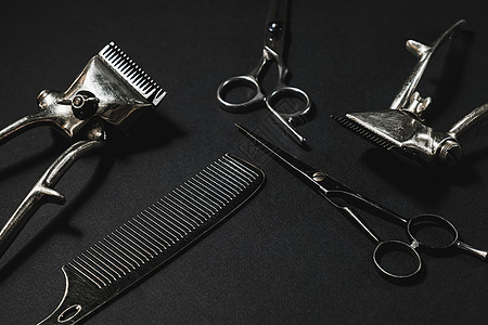 在黑色的表面上是旧的理发工具 两把老式手动理发剪 梳子 美发剪刀 黑色单色 对比阴影 水平的男性马夫奢华修剪理发皮肤剪切安全工作图片