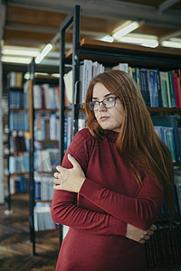 一个拿着书架的女孩 图书馆里的一个学生书店中学天线架子女士智力知识女性同学教育图片