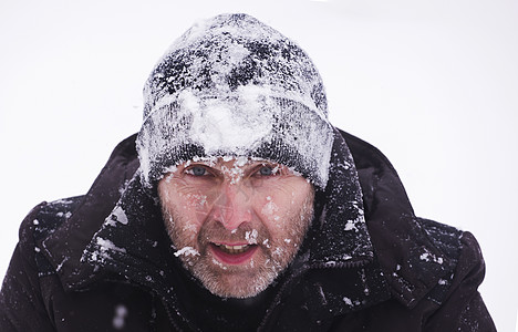 一个戴针织帽的男人的近身肖像 上面盖着雪露天低温活动休闲胡须涂层下雪人脸帽子情感图片