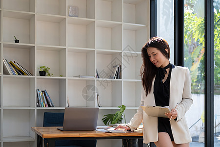 有魅力的亚洲女性在家里的客厅里查税 银行账户余额和计算开支图片