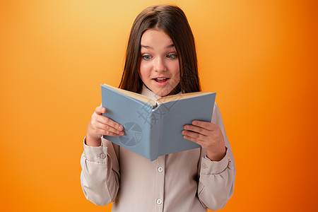 有着橙色背景书籍的聪明少女女孩的肖像考试学习班级笔记本家庭作业教育女性孩子们头发微笑图片