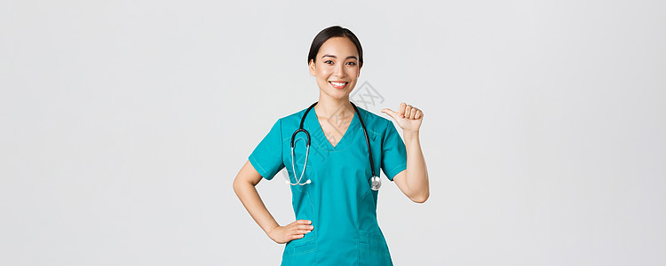 Covid19 医护人员 流行病概念 专业自信的亚洲女医生 穿着磨砂膏的护士指着自己微笑 保证她知道该做什么 白人背景症状暴发感图片