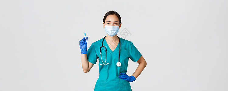 Covid19 冠状病毒疾病 保健工作者概念 自信的女性护士 戴医疗面具和橡胶手套的医生 持有注射针筒并携带疫苗 站立白种背景流图片
