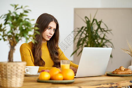 漂亮的漂亮女性 一头金发长发 坐在家里用笔记本电脑工作图片