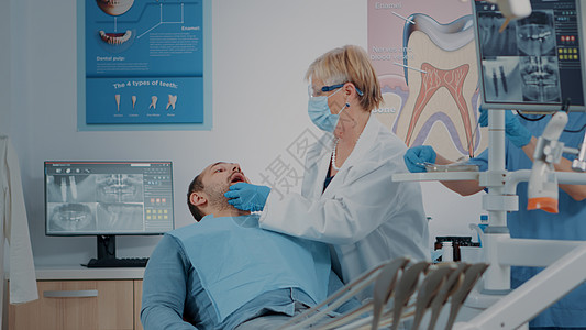 使用牙科工具检查假牙的戴面罩牙医图片