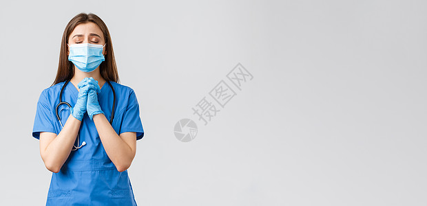 Covid19 预防病毒 健康 医护人员和检疫概念 有希望的女护士或医生穿着蓝色磨砂膏 医用面具 为冠状病毒感染患者的生命祈祷防图片