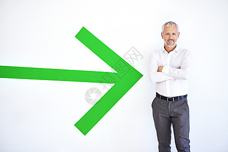 为您指明合适的人选 站立反对与指向他的一个大绿色箭头的白色背景的一个成熟商务人士图片