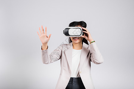 在虚拟现实体验期间 微笑的女性自信兴奋地佩戴VR头盔装置触碰空气游戏齿轮娱乐技术眼镜模拟器创新工具展示电子图片