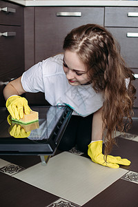 女人 穿着保护手套 在厨房用抹布清洁炉图片