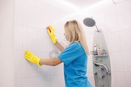 有特别清洁海绵清洗墙的女人 在浴室的地板上拉平了图片