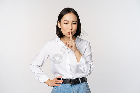 年轻亚洲成年女子的肖像 她们静默 说嘘 按对嘴唇 分享秘密 不说禁忌姿态 站在白背景上站立手臂售货员成人女孩办公室广告技术商务公图片