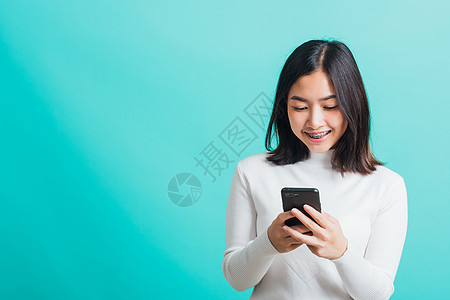 妇女微笑 她拿着并打短信阅读短信互联网头发手机网络乐趣女性滚动青少年图片