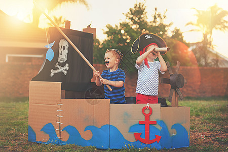 这些小海盗只是想找点乐子 一个可爱的小男孩和他的兄弟在纸板箱制成的船上玩海盗的镜头图片