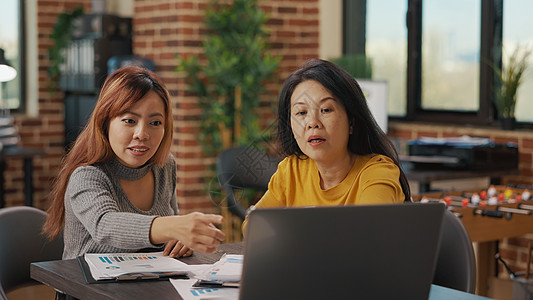 亚洲妇女从笔记本电脑屏幕看研究金融图片