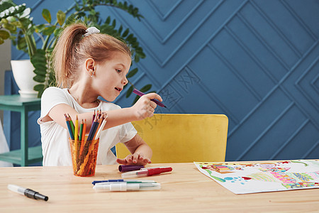 美术学校的可爱小女孩用铅笔和标志画出她的第一部绘画 并绘制了铅笔和标记图片