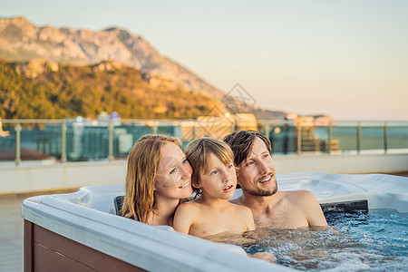 年轻无忧无虑的快乐微笑幸福家庭的肖像在享受快乐的旅行时刻假期期间在热水浴缸中放松 绿色大山背景下的生活悲伤身体活动女士航程福利女图片