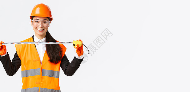 自信的亚洲职业女建筑师测量布局 戴安全帽和制服 拿着卷尺 微笑着高兴 对施工期间取得的成果感到满意工厂电子商务装修维修工程师建设图片