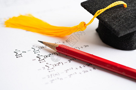 在教育学校学习数学公式练习纸上的毕业脱衣帽和铅笔试卷背景图片