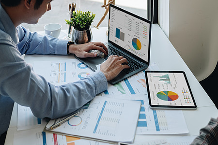 商务人士在笔记本电脑上工作和分析财务报告 计算财务文件数据图的统计数据 用于新项目的业务战略和工作场所的市场增长图片