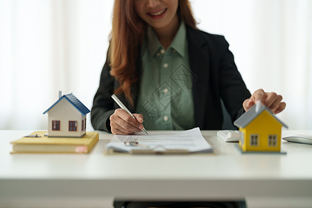 亚洲女商务人士签署家庭建筑模型背后的合同房地产概念桌子信用套装协议木头抵押建造人士文档贷款图片
