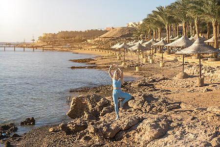 有魅力的健康女性练习侧弓步 在阳光明媚的日子里在沙滩上锻炼 健康的生活方式 户外锻炼海洋成人运动装运动服运动员跑步天空运动海岸线图片