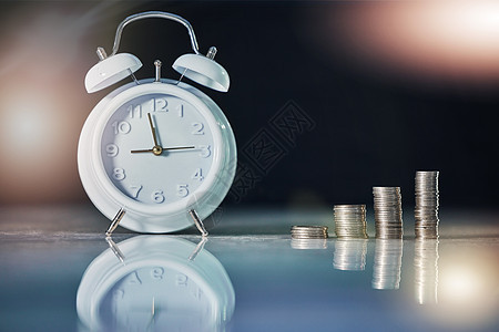 投资和回报需要时间 在空办公室的桌子上拍摄闹钟和硬币图片