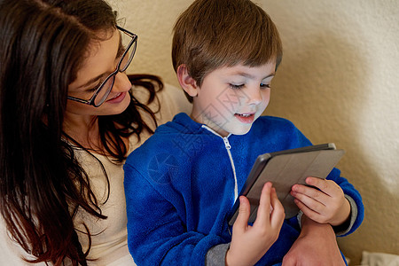 现在连小孩都懂科技了 在家里用数字平板电脑拍到一个母亲和儿子的身影 在家中背景图片