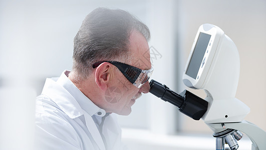 科学家仔细地通过显微镜看望着男人生物学药品测试教育外套抗体学习医生专家图片